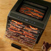 Bacon being dehydrated in a digital smoker on a wooden surface